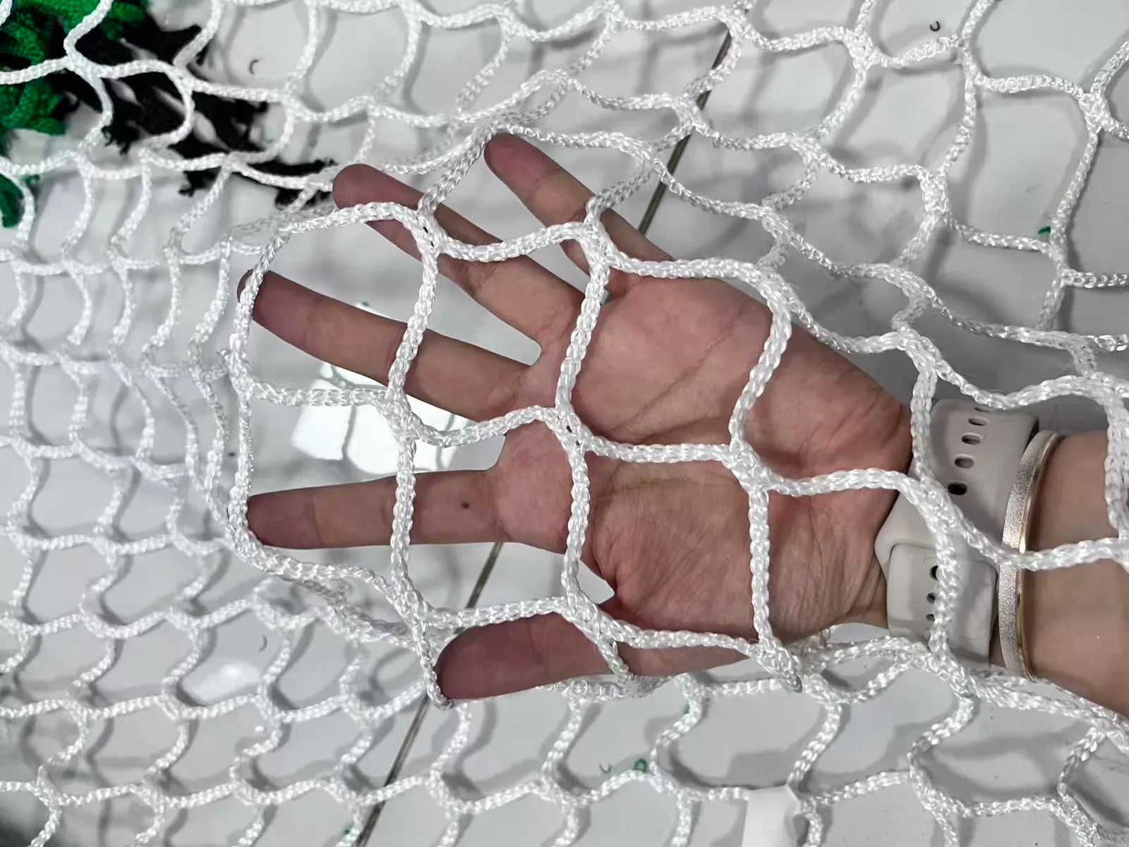 Factory sample of black knotless polyester ball stop netting, 45 mm mesh with 4 mm twine, held in hand